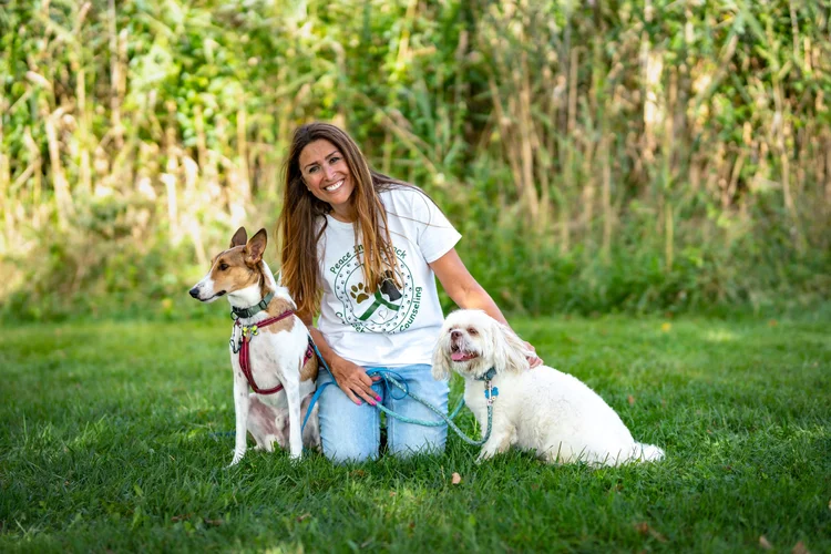 Nancy kneeling on grass with her two dogs